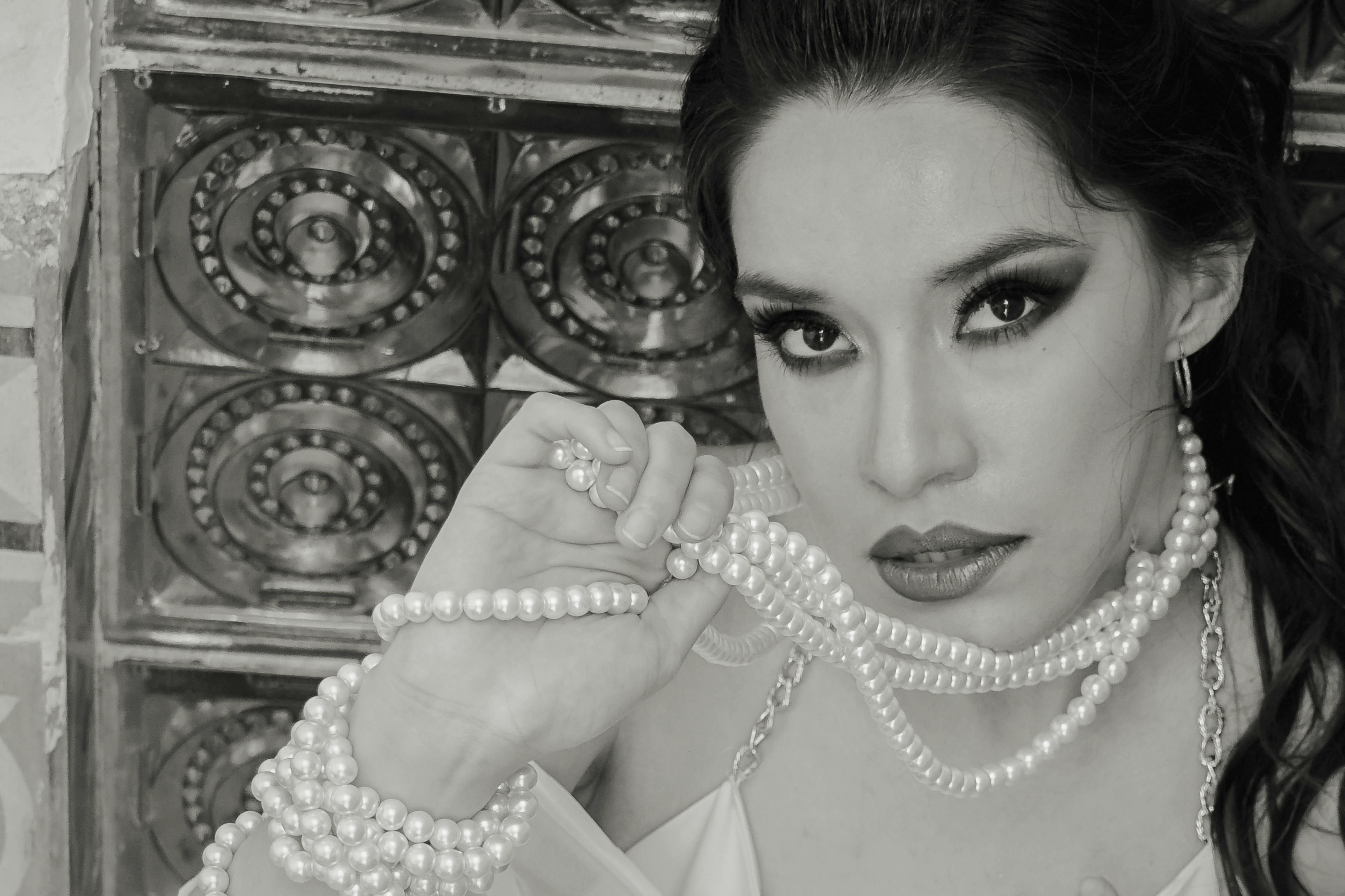 Black and white portrait of a woman with pearl jewelry, showcasing elegance and style.