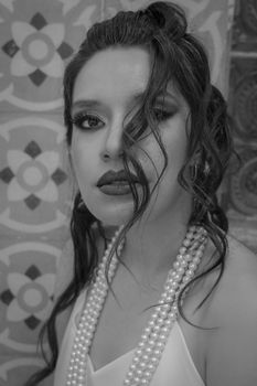 Elegant black and white portrait of woman with pearls and dramatic makeup.
