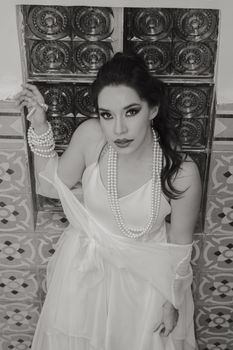 Stylish black and white portrait of a woman with pearls, exuding elegance and glamour.