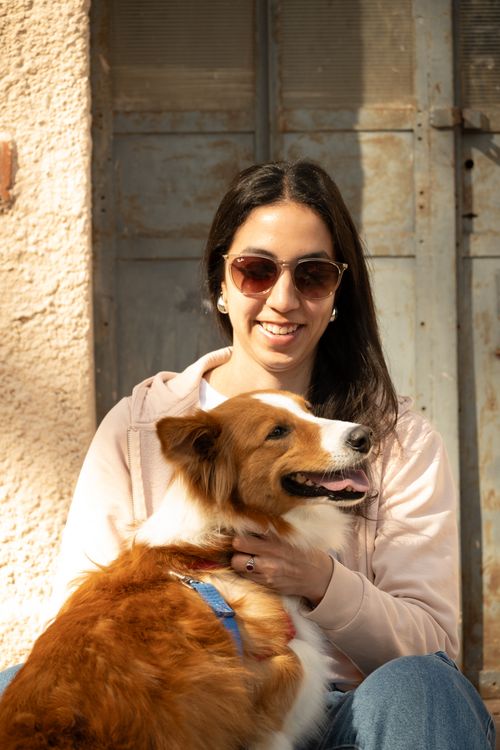 Free Smiling woman wearing sunglasses cuddling with her fluffy dog outside. Stock Photo