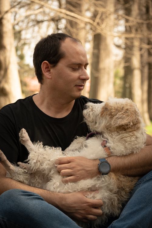 Free Casual moment of a man holding his dog in a serene forest setting, highlighting companionship. Stock Photo