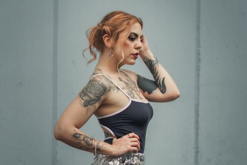 Free Portrait of a woman with tattoos and red lips posing against a gray background. Stock Photo