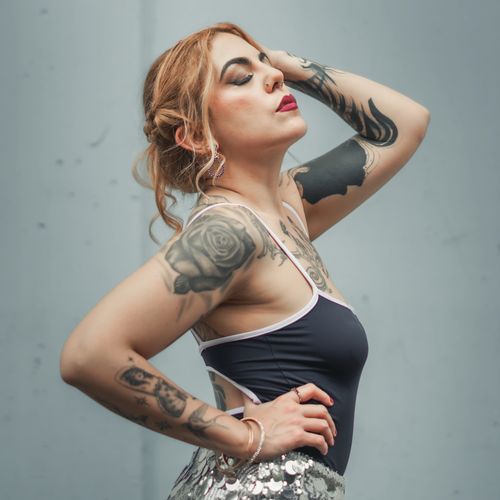 Free Artistic portrait of a fashionable woman with tattoos posing in black top and sequined skirt. Stock Photo