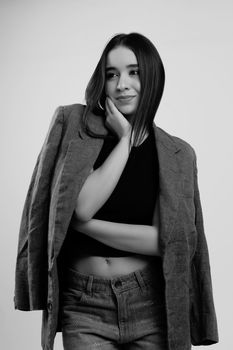 Black and white portrait of a young woman posing confidently in a casual outfit and jacket.