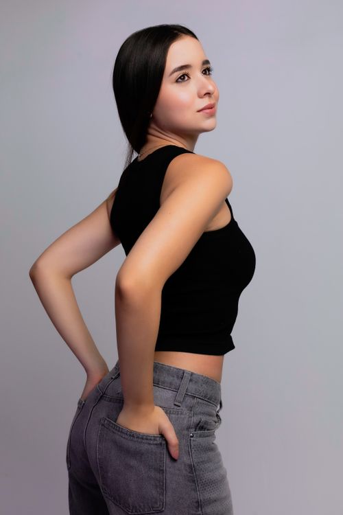 Free A stylish and confident young woman posing against a neutral background in a studio setting. Stock Photo