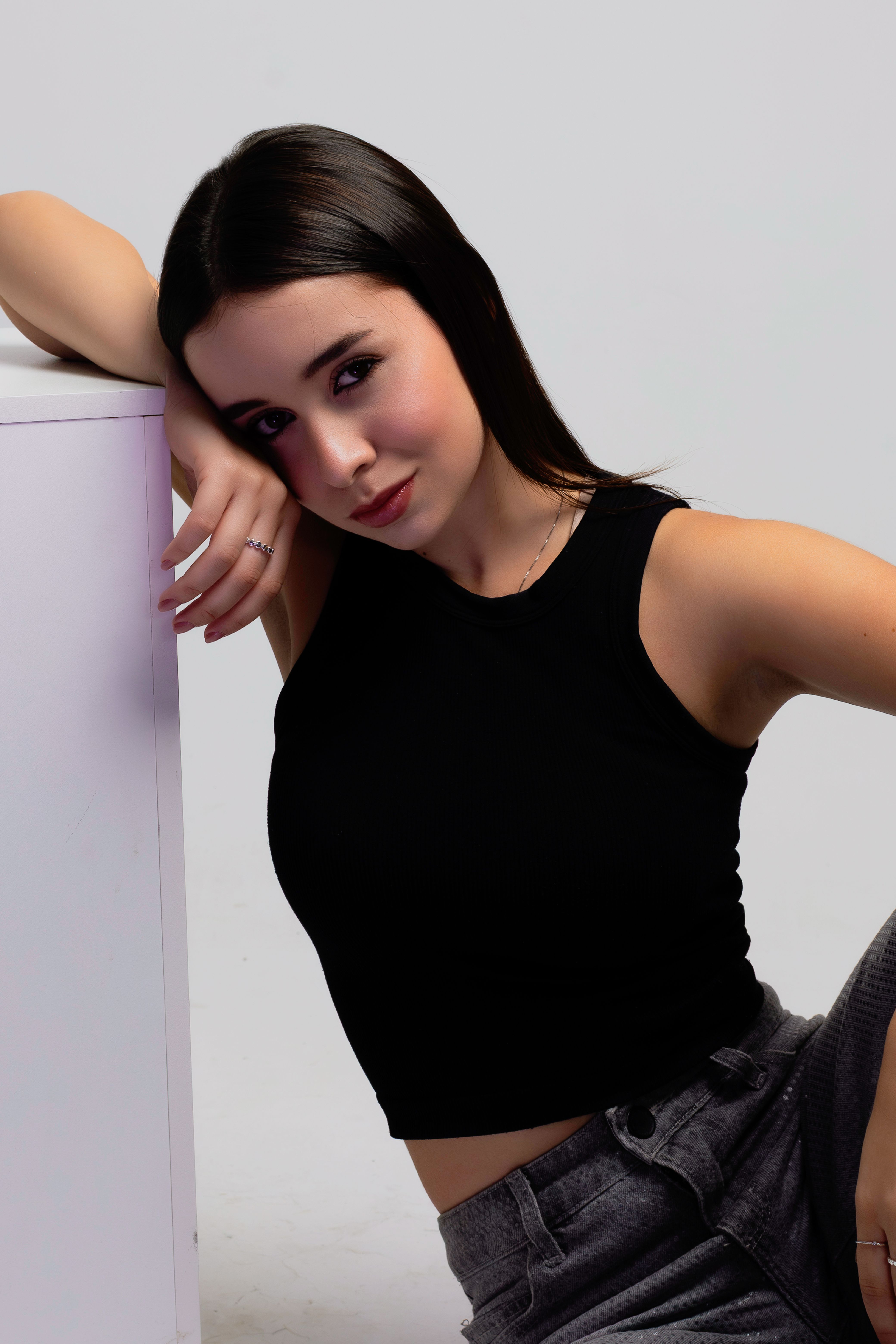 Portrait of a young woman in a black top posing indoors with a confident expression.