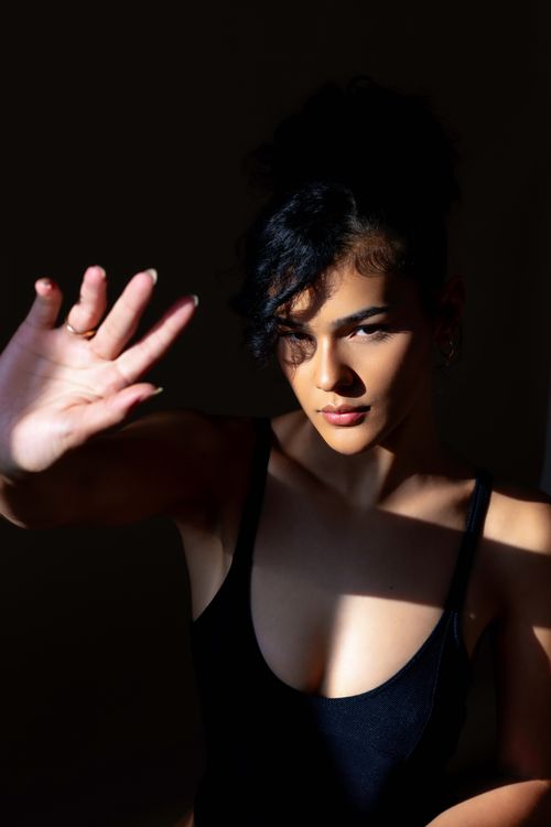 Free A striking portrait of a woman in dramatic lighting casting shadows indoors. Stock Photo