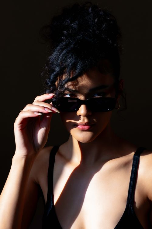 Free Chic portrait of a woman in sunglasses with dramatic lighting, exuding confidence. Stock Photo