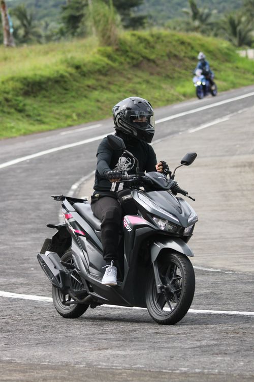 Free A motorcyclist in protective gear riding a scooter on a paved road in Tabaco City, Philippines. Stock Photo