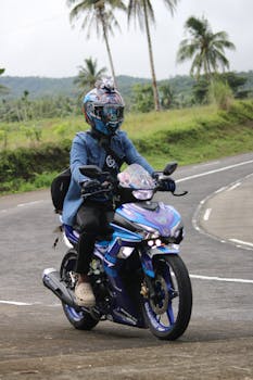 A motorcyclist embarks on a scenic ride along a lush, winding tropical road.