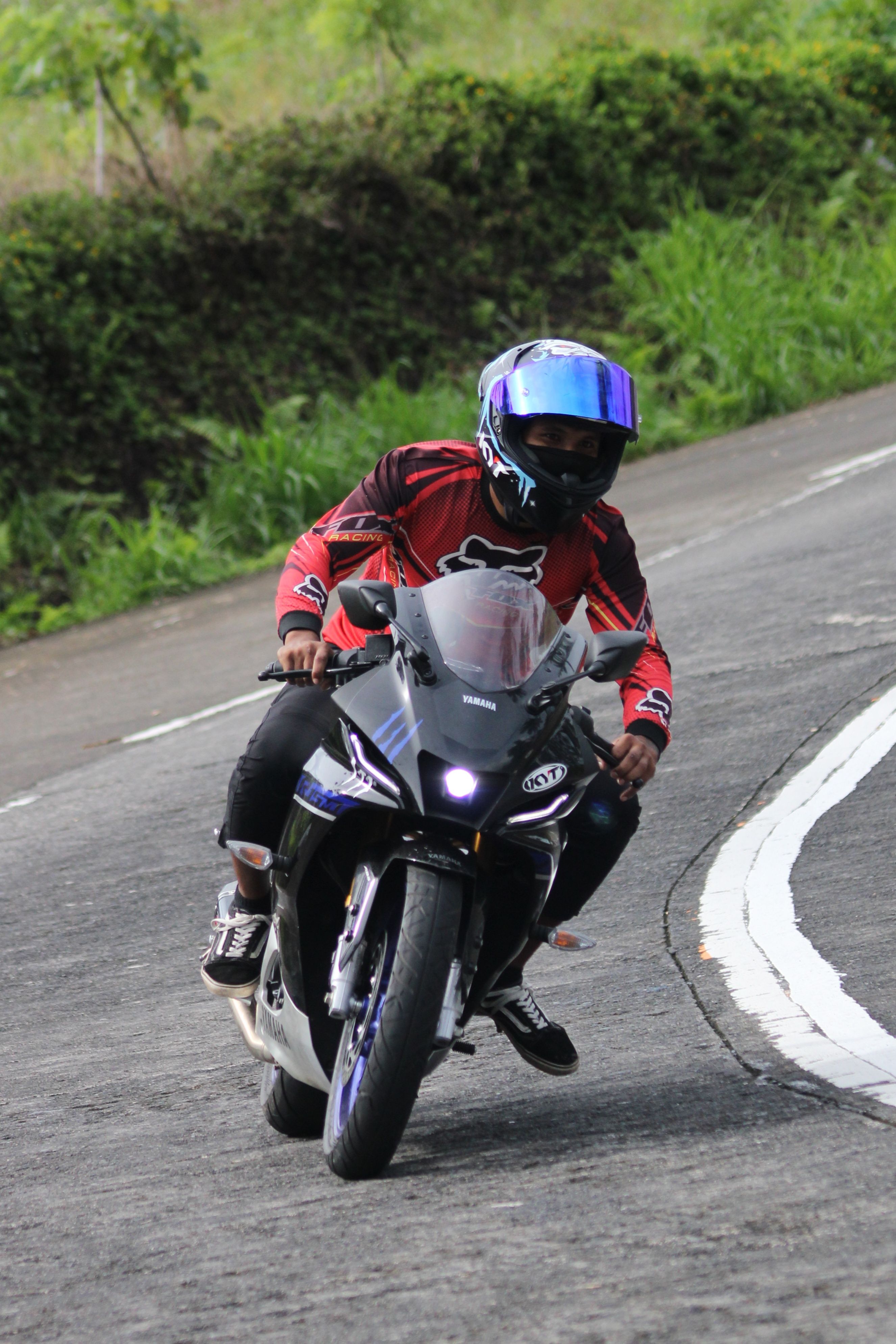 A motorcyclist in full gear skillfully navigates a curve on a rural road.