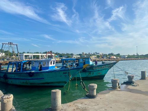 Free Blue fishing boats docked at a sunny pier with clear skies and calm waters. Stock Photo