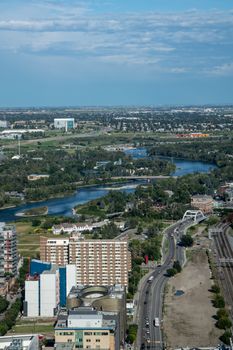 Stunning aerial view showcasing a river winding through an urban landscape with lush greenery and tall buildings under a clear sky.