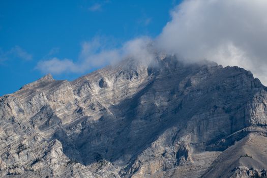 Stunning view of a rocky mountain peak with clouds in Banff National Park.