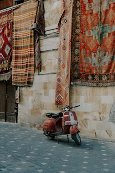 Vintage scooter parked by a wall adorned with colorful tapestries.