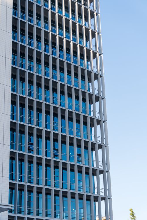 Free Urban highrise with glass windows reflecting blue sky. Ideal for business themes. Stock Photo