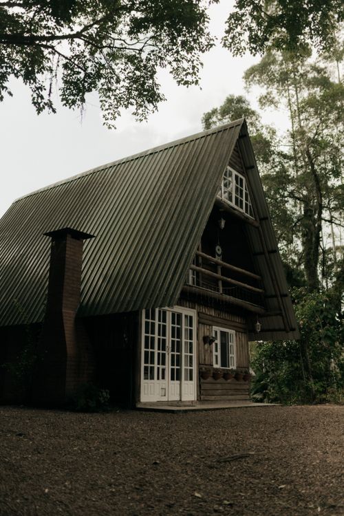 Free A picturesque A-frame cabin surrounded by lush trees, creating a serene forest escape. Stock Photo
