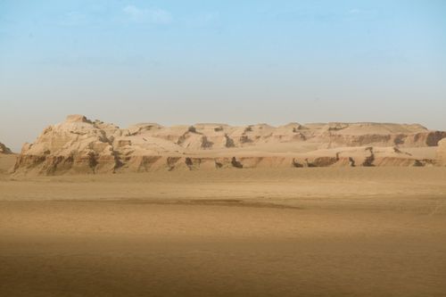 Free Expansive desert scene with rocky formations under a clear blue sky. Stock Photo