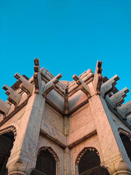 Free A low angle view of historic stone architecture with intricate designs under a vivid blue sky. Stock Photo