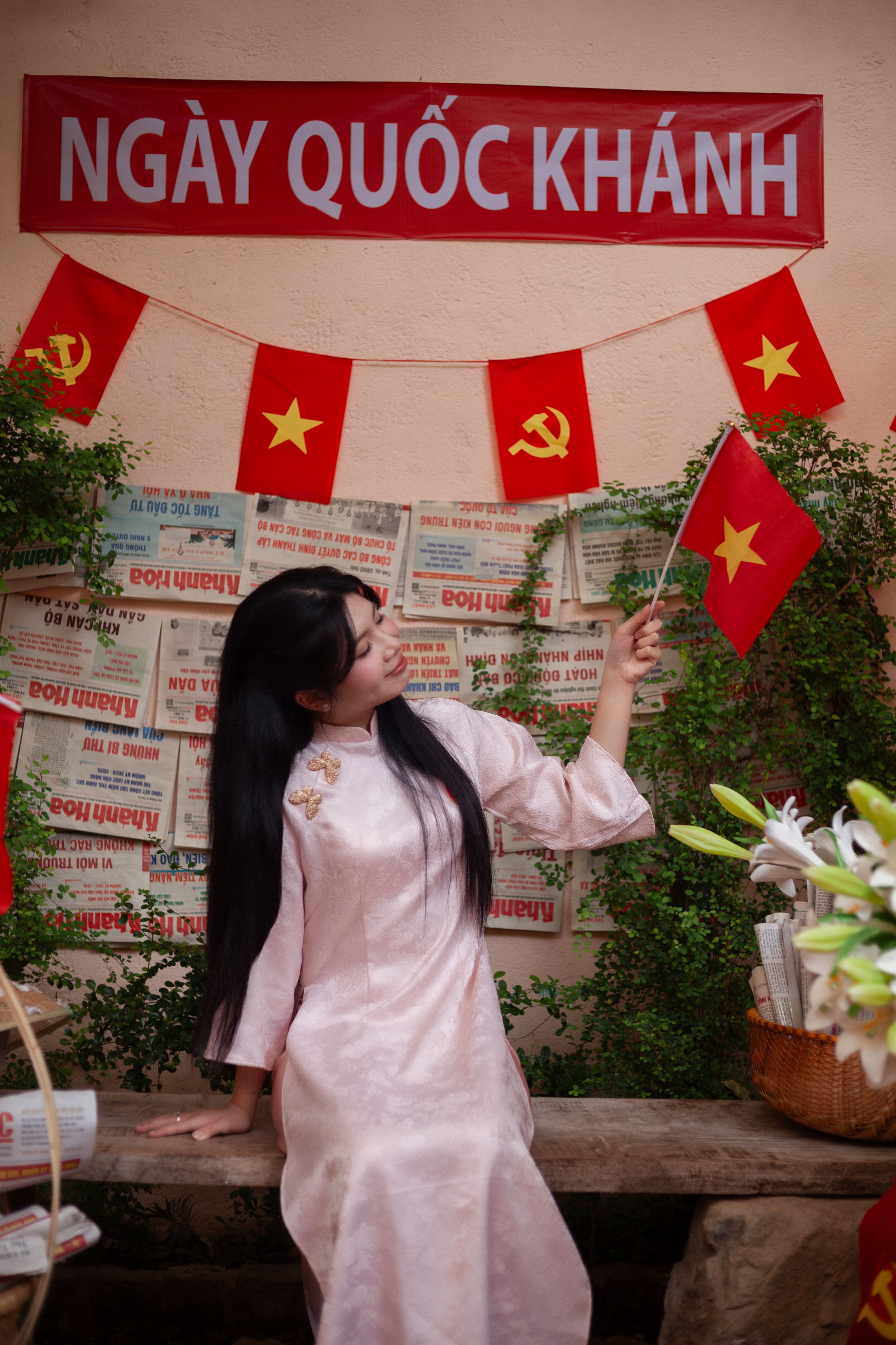 Woman in traditional dress celebrates Vietnam National Day with flags and decor.