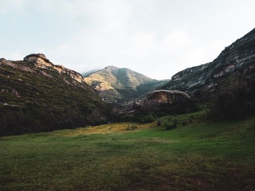 Free Serene mountain landscape with lush greenery and rocky formations under a clear sky. Stock Photo