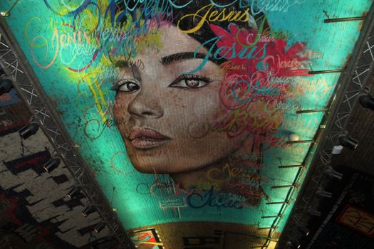 Vibrant ceiling mural depicting a woman's face surrounded by artistic text in bold colors.