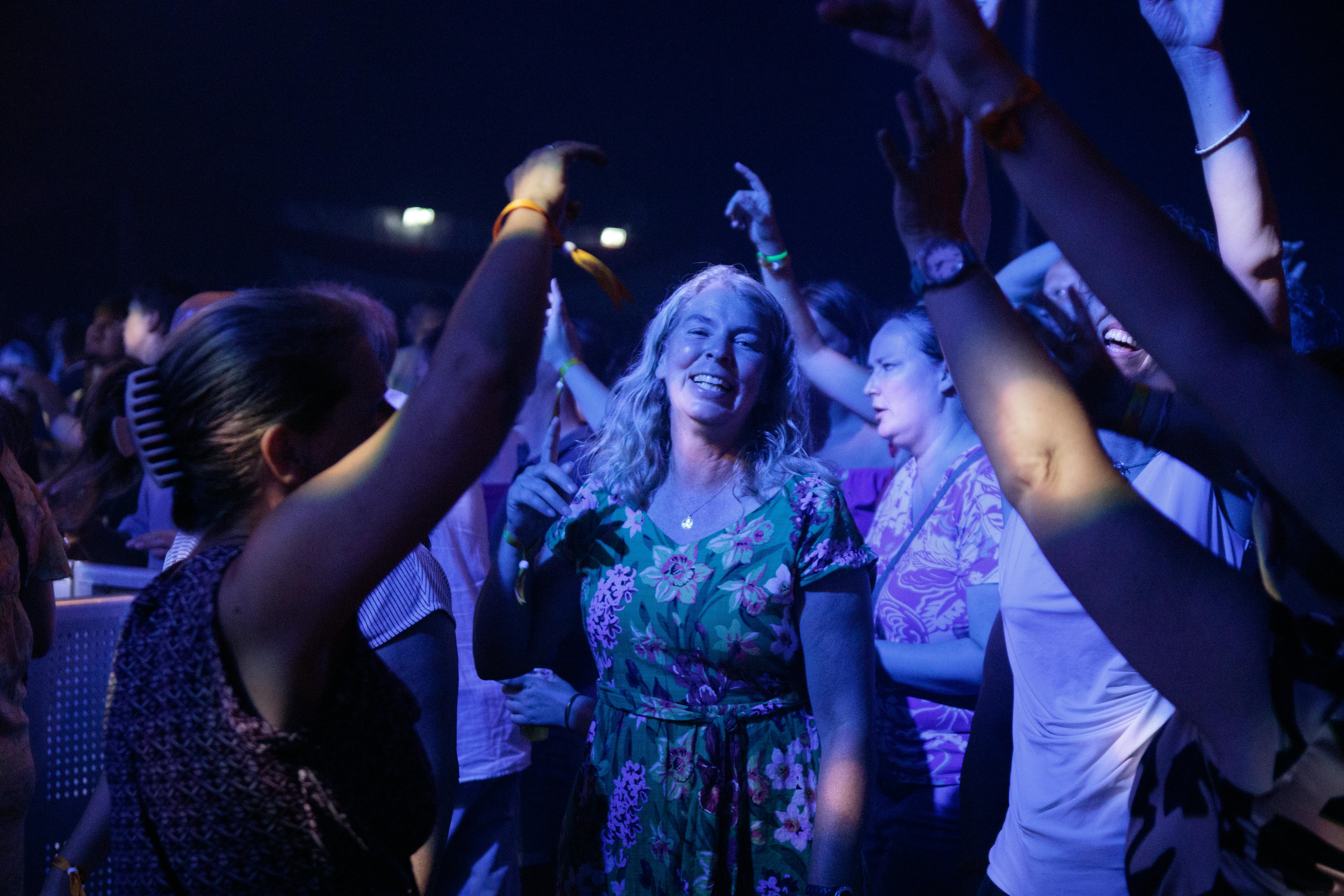 A lively crowd enjoying a night party with vibrant lighting and dancing.