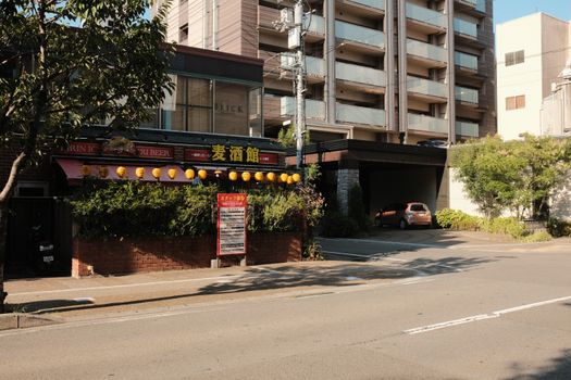 Image of a Japanese izakaya with lanterns, adjacent to a modern residential building.