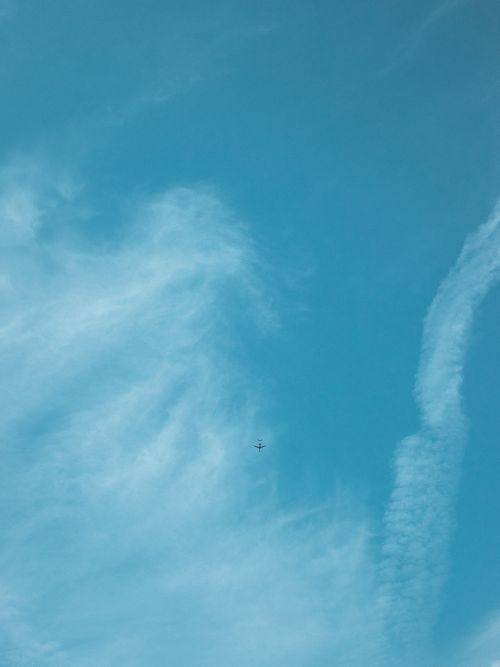 Free A small airplane soars through a bright blue sky, surrounded by clouds. Stock Photo