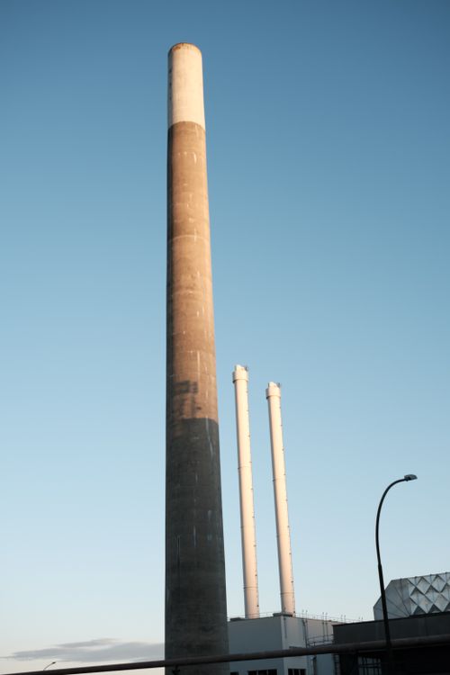 Free Tall industrial chimneys reaching into a clear blue sky, symbolizing industry and energy. Stock Photo