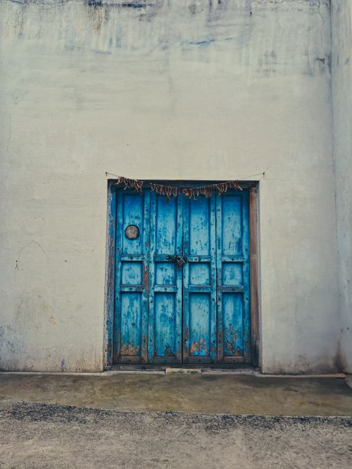 Free Weathered blue doors on a rustic wall in Erode, India, capturing vintage charm and cultural ambiance. Stock Photo