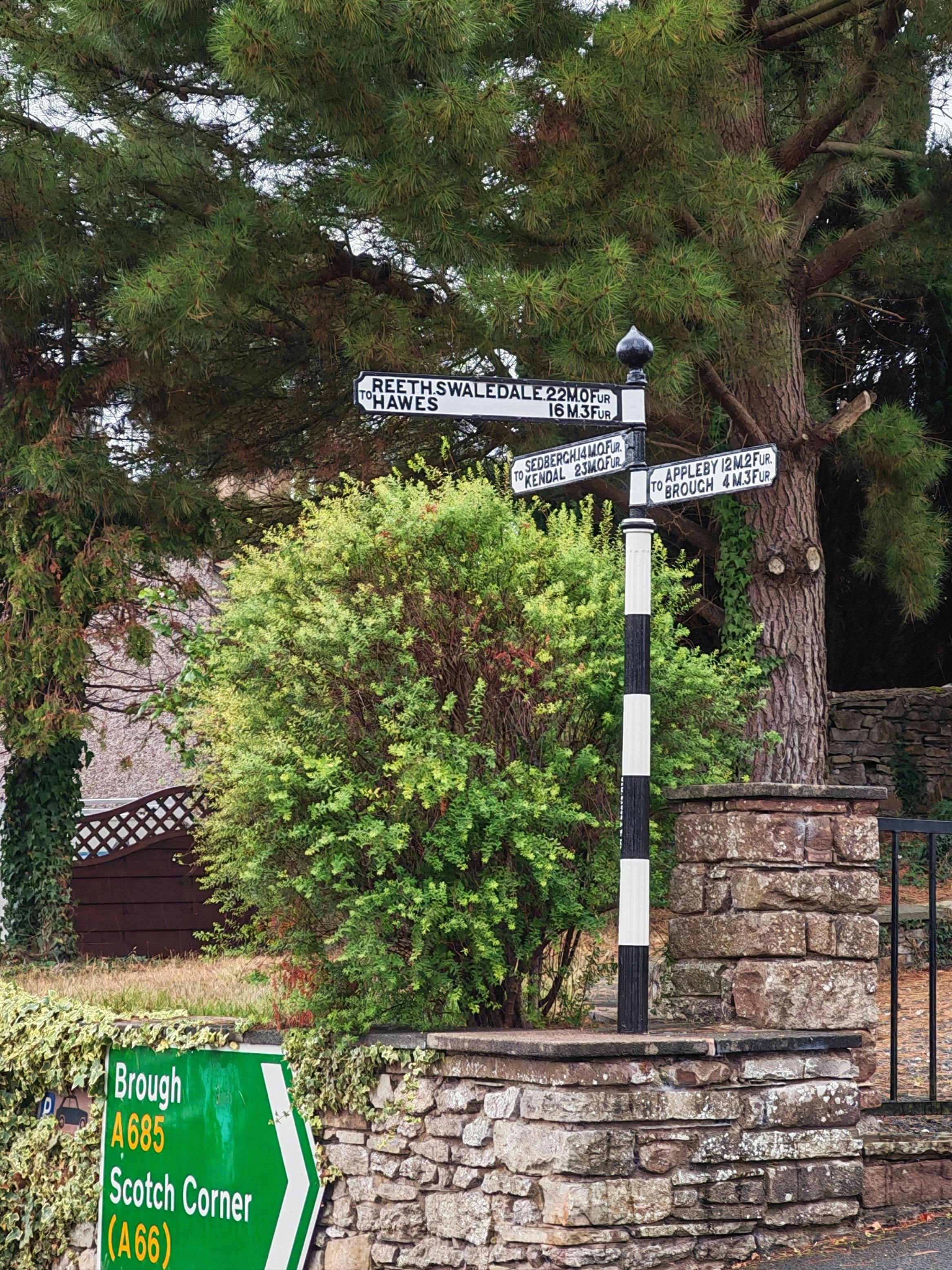 Kostnadsfria En traditionell brittisk vägskylt omgiven av frodig grönska i en lantlig miljö. Stock foto