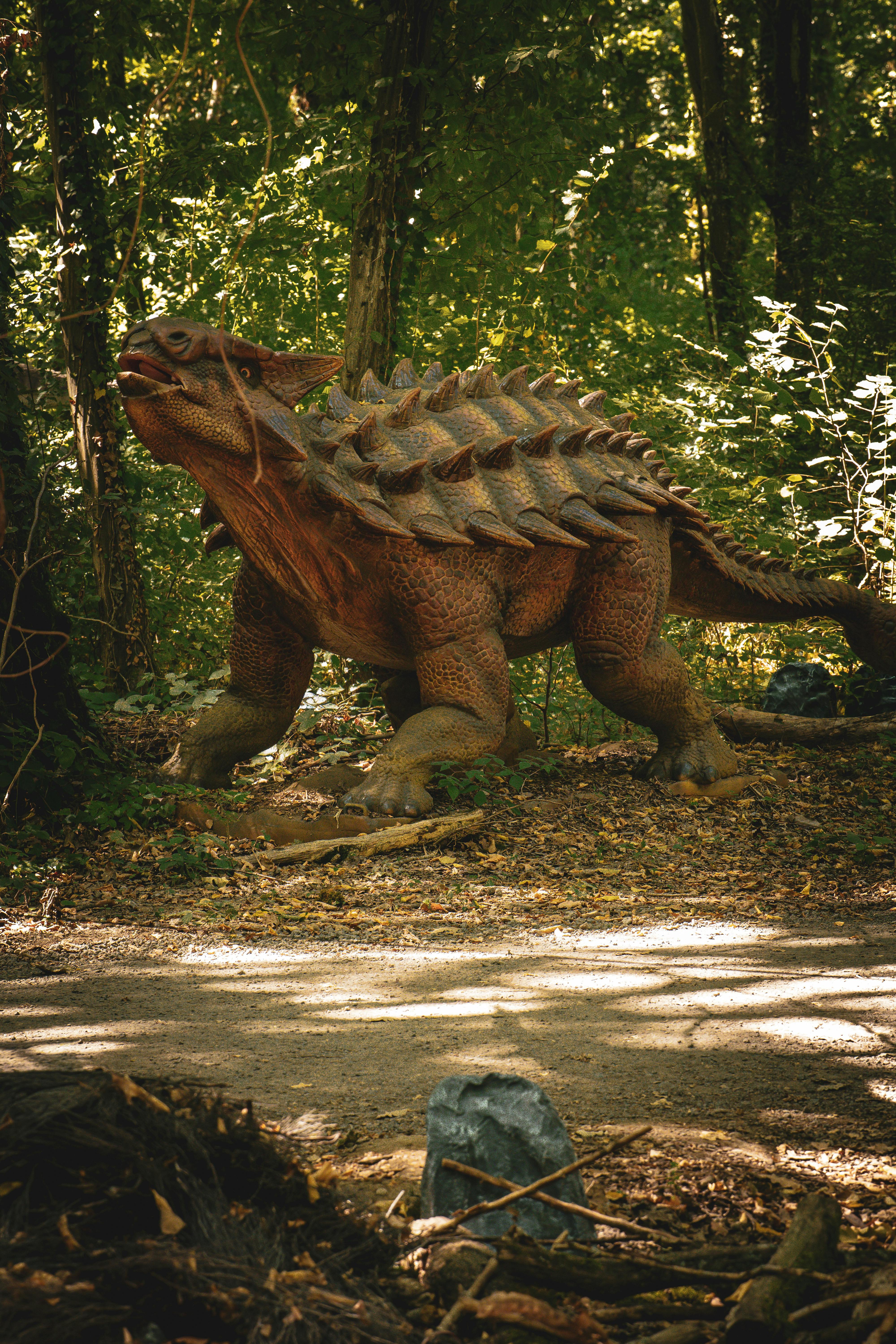 common:alt.prefix Estàtua de dinosaure de mida real enmig d'un bosc exuberant, capturant l'essència prehistòrica. common:alt.postfix