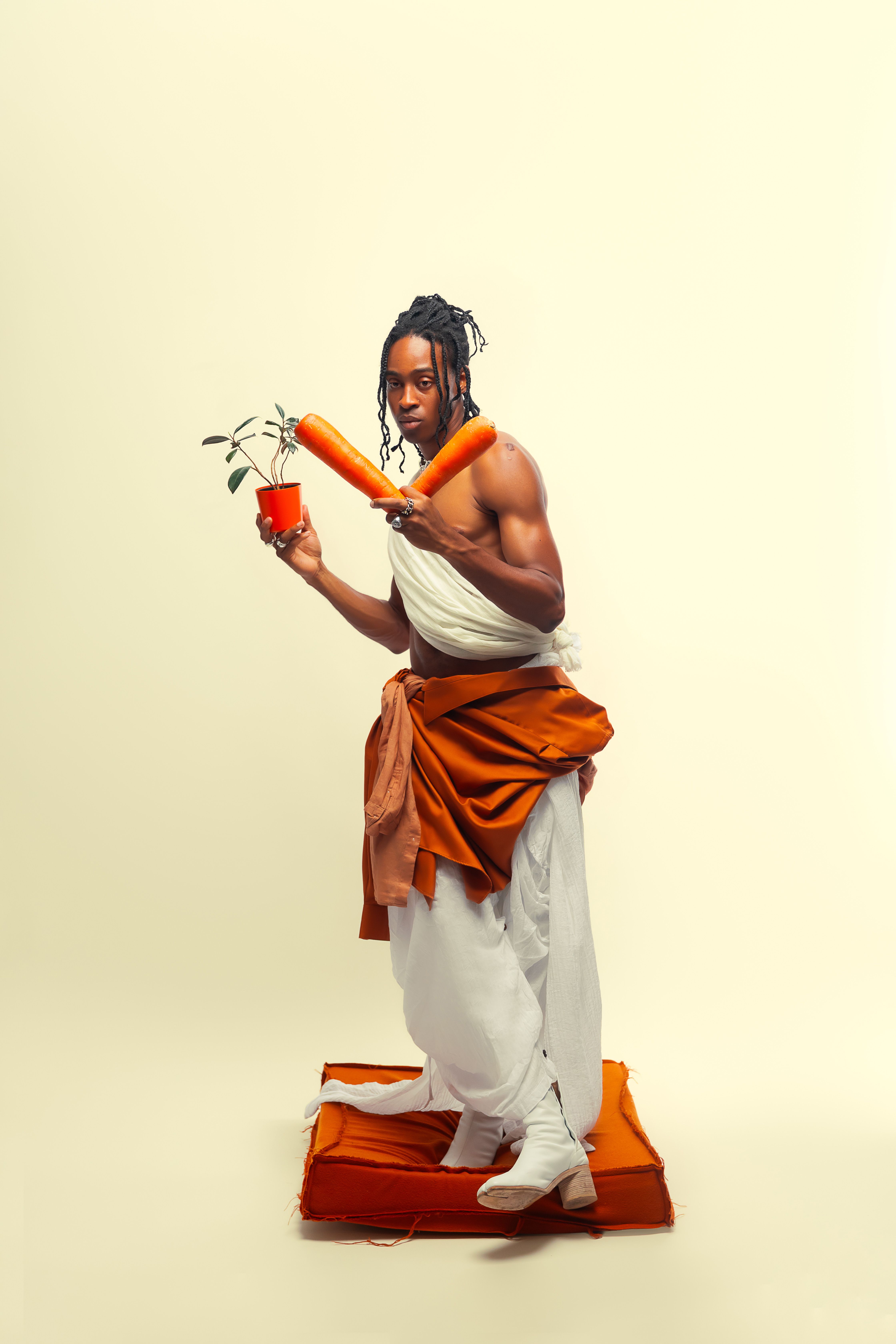 Unique portrait of a man in traditional attire holding carrots and a plant.