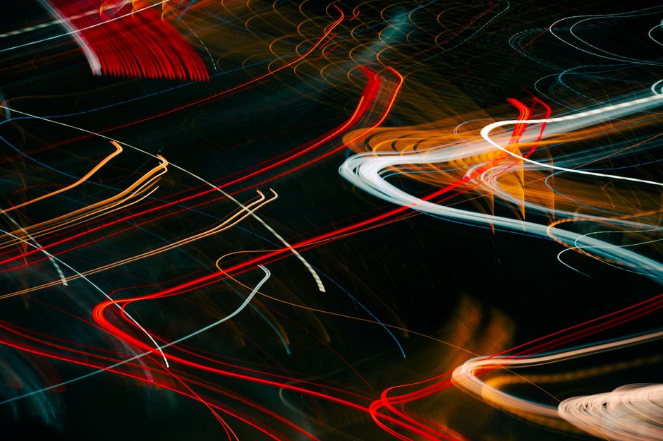 Dynamic abstract photo of colorful light trails captured at night, depicting city movement.