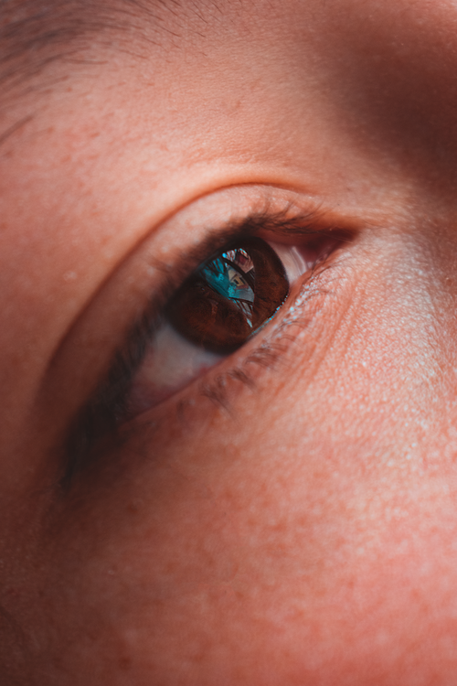 Free Detailed macro shot of a human eye reflecting vibrant colors, highlighting brown iris. Stock Photo