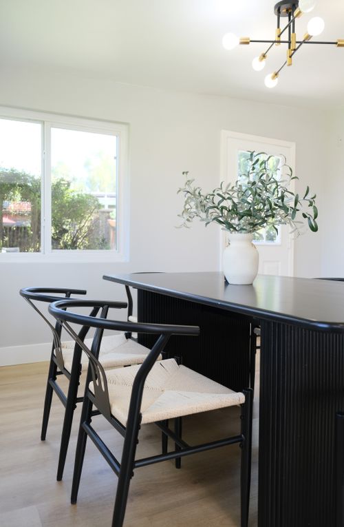 Free Elegant dining room with a black table, chairs, and a vase of greenery, showcasing modern design. Stock Photo