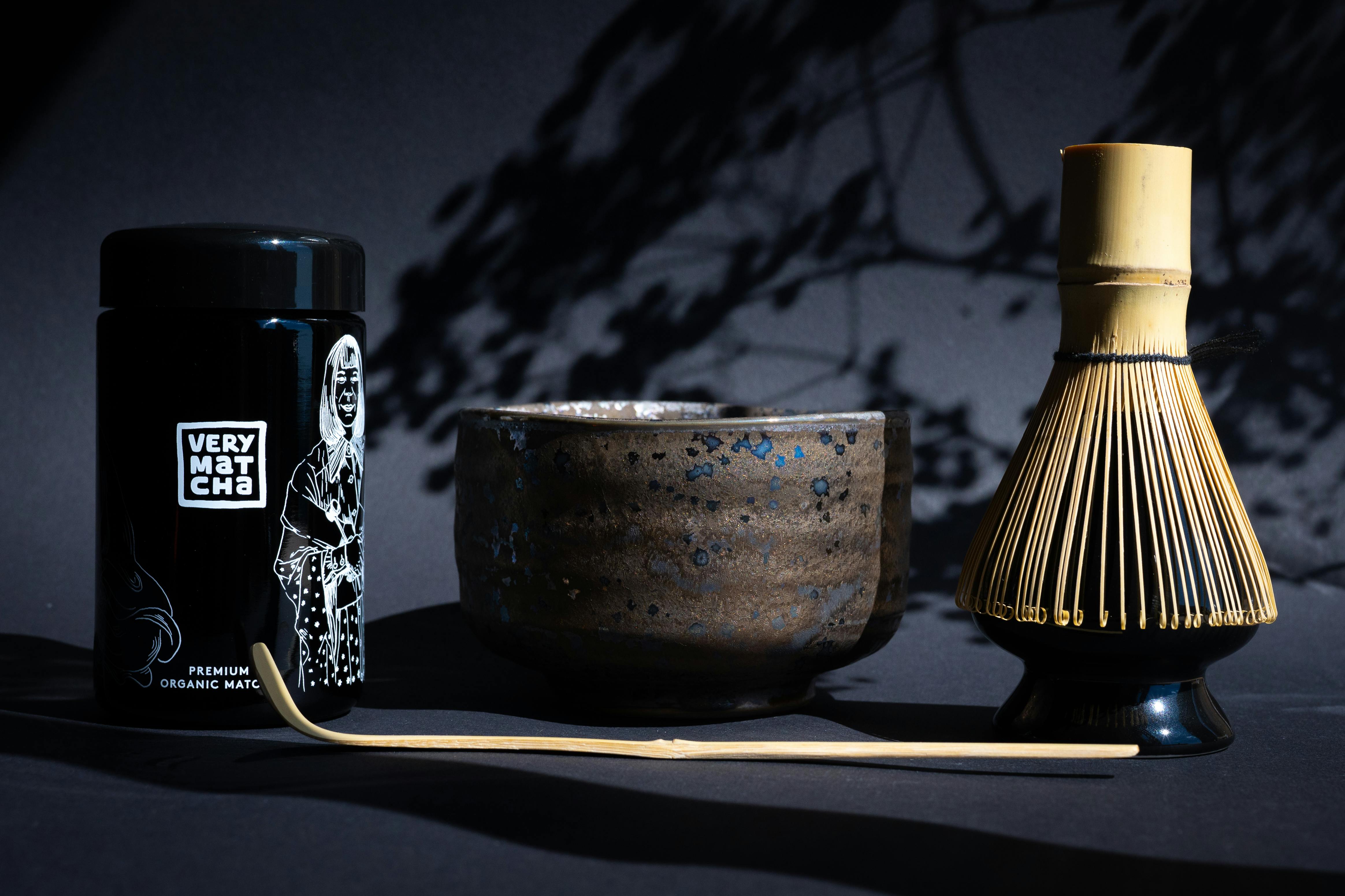 A traditional matcha tea ceremony setup featuring bamboo whisk, matcha bowl, and tea caddy.