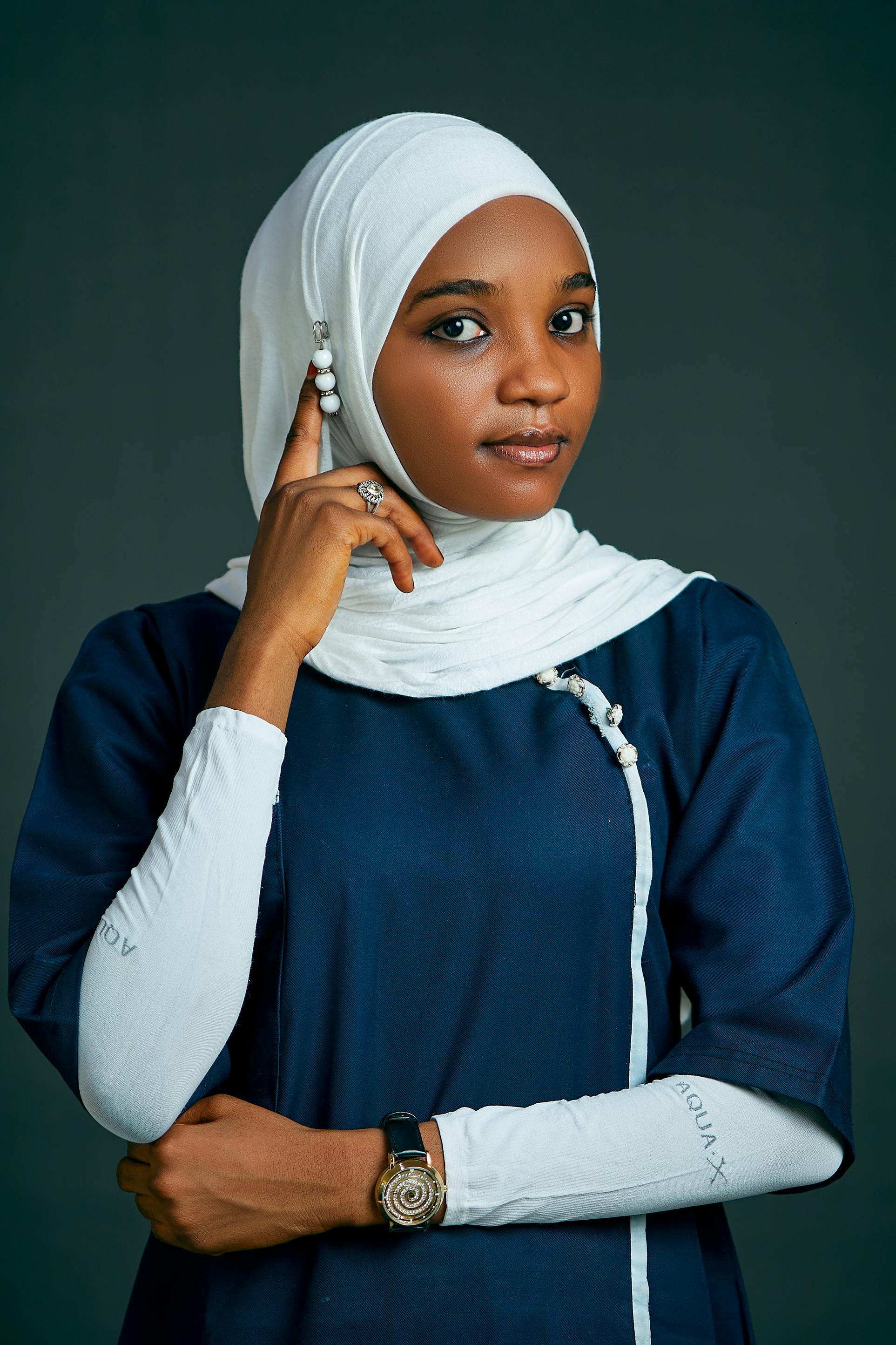 Elegant portrait of a confident woman in a white hijab and blue dress, exuding grace and style.