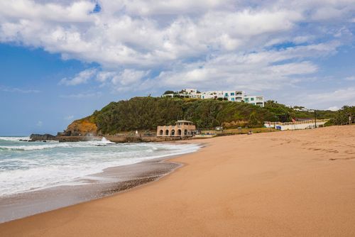 Free A picturesque beach with hillside architecture under a bright sky, showcasing serene coastal beauty. Stock Photo