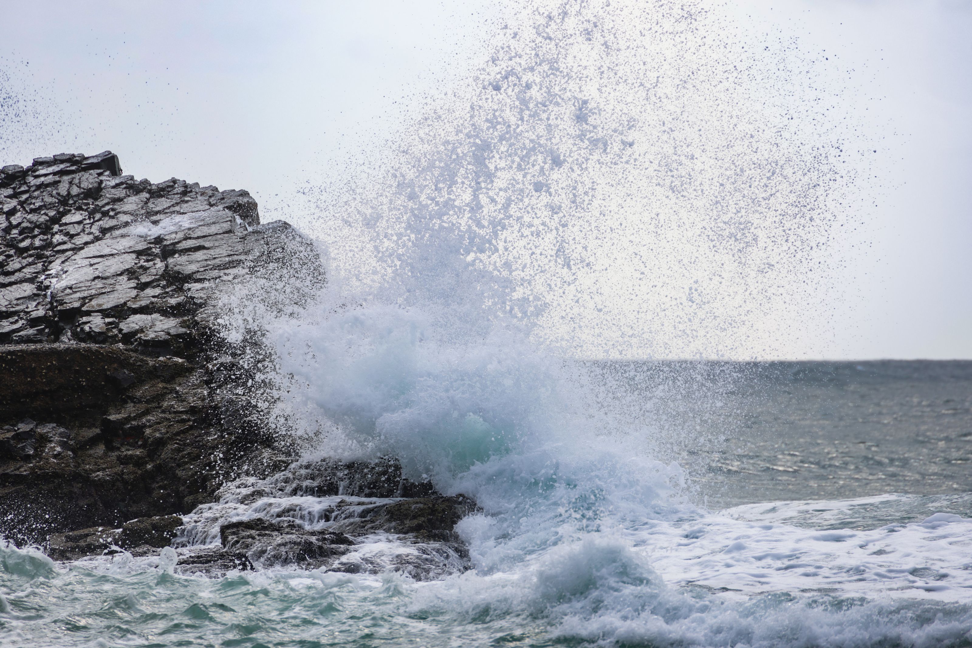 Powerful ocean wave crashes against rugged rocks, capturing the essence of nature's force.