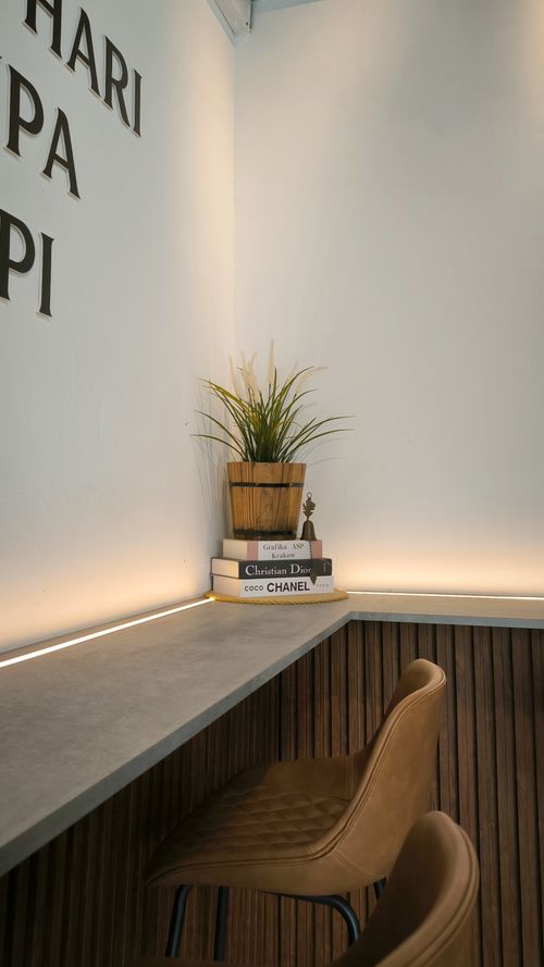 Free Cozy cafe corner in Malaysia featuring leather chair, plants, and stylish decor books. Stock Photo