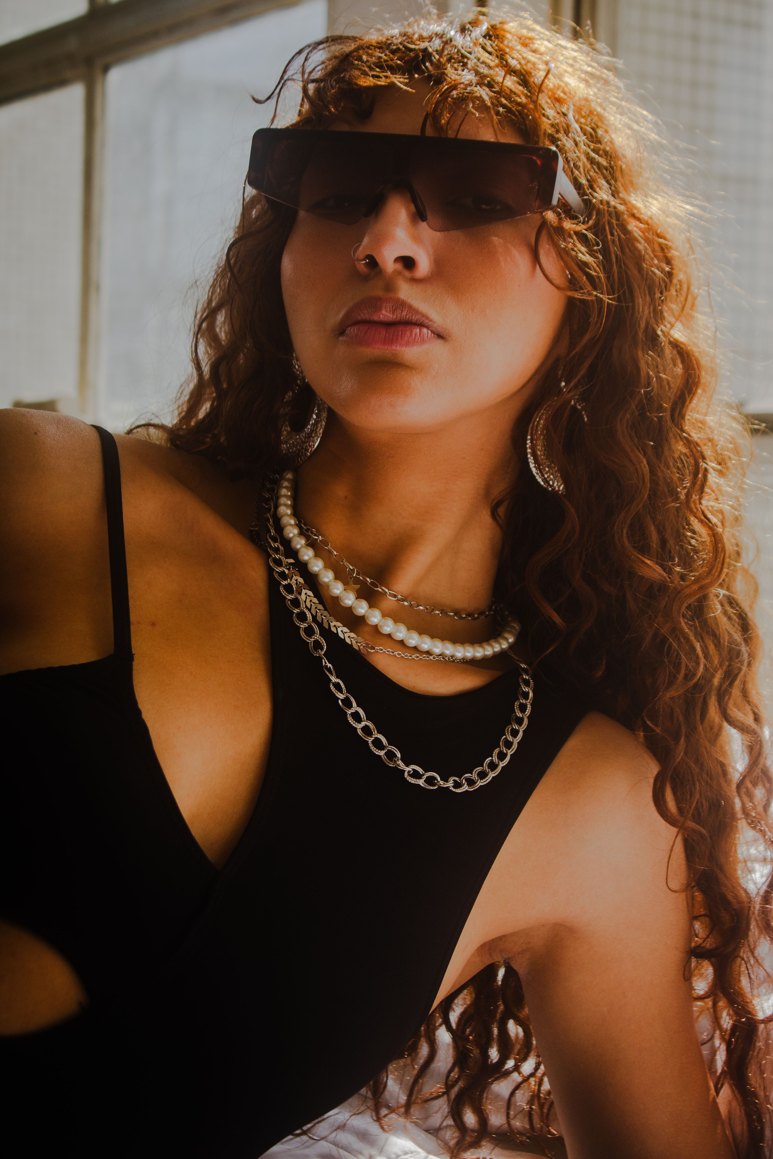 Mulher elegante usando óculos escuros e joias em ambiente urbano, São Paulo.