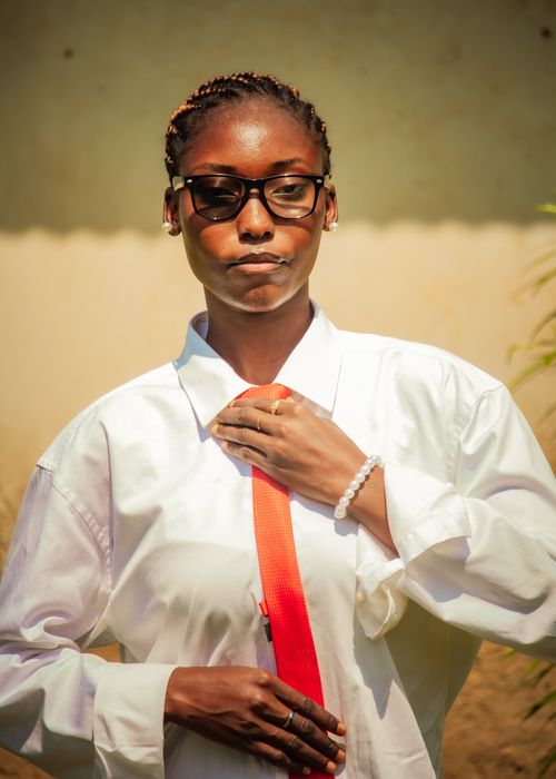 Free Portrait of a stylish young adult adjusting a red tie outdoors on a sunny day. Stock Photo