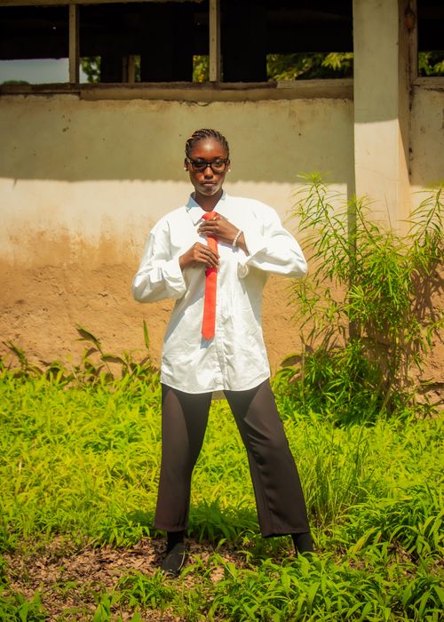 Free Teenager in a white shirt and red tie poses confidently outdoors by an old building. Stock Photo
