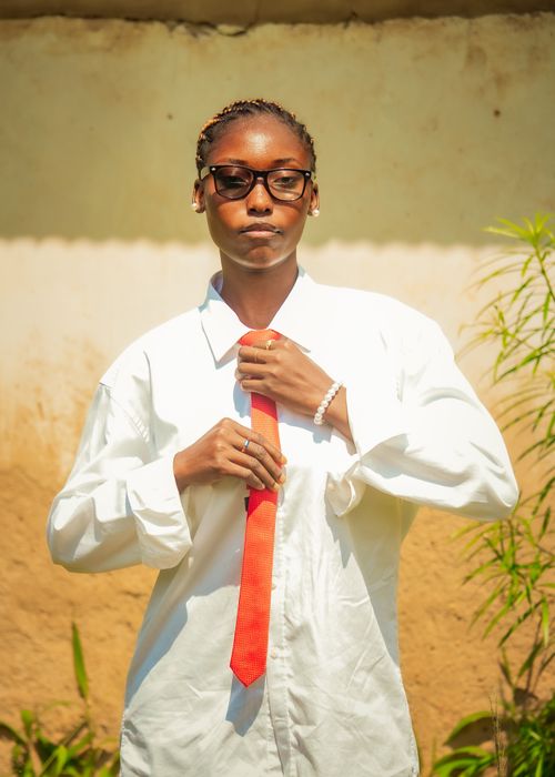 Free Confident young adult adjusting red tie in sunny outdoor setting, showcasing professionalism. Stock Photo