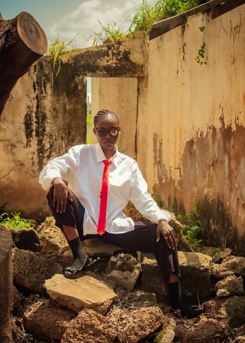 Free Confident woman poses in abandoned ruins, wearing a white shirt and striking red tie. Stock Photo