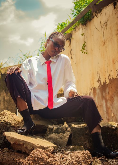 Free Stylish outdoor portrait featuring bold fashion with a red tie against a rustic wall. Stock Photo