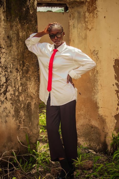Free A person poses confidently in a red tie and sunglasses against an outdoor rustic background. Stock Photo