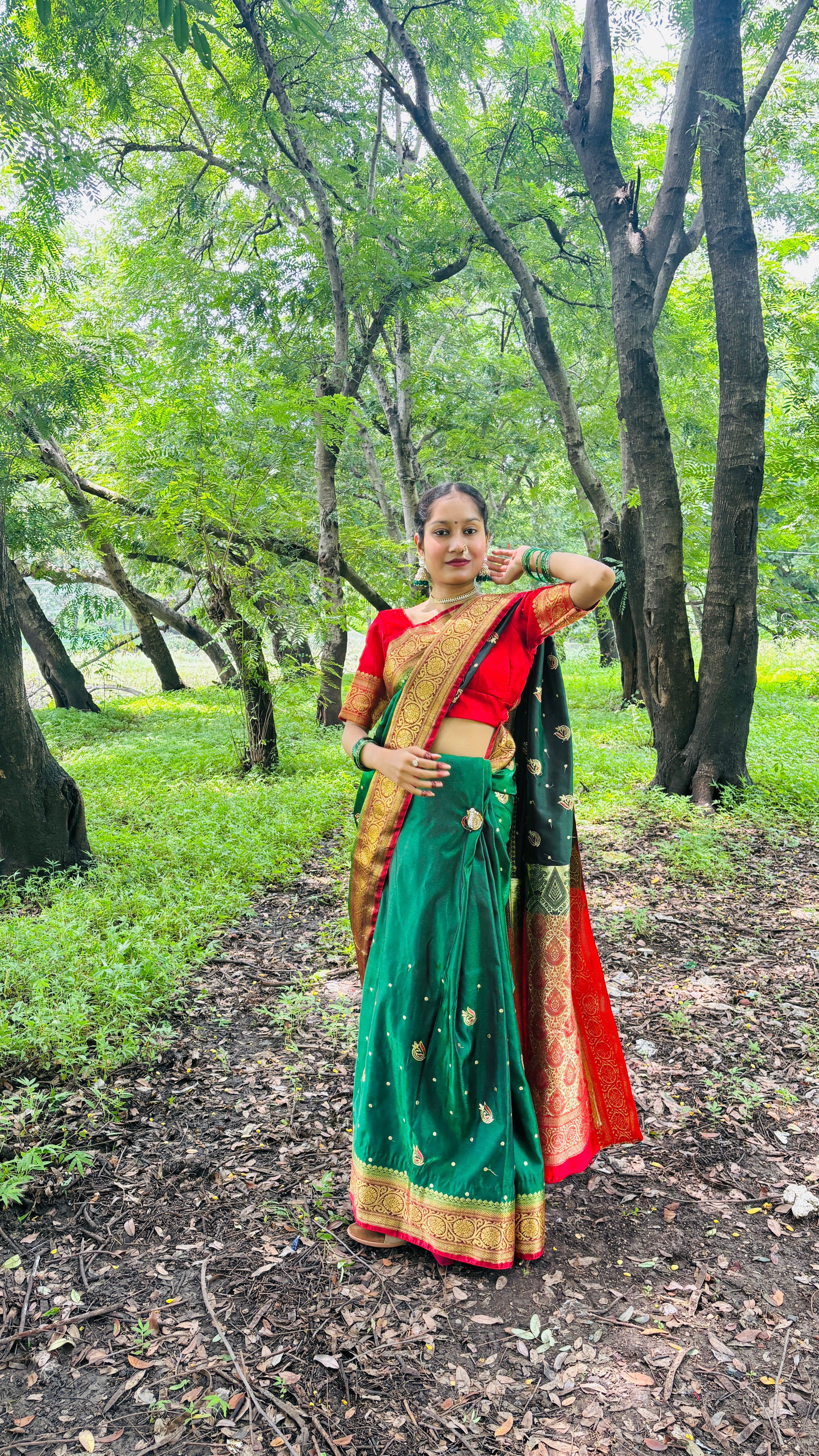 A woman wearing a colorful saree stands gracefully in a lush forest, embodying tradition and nature.